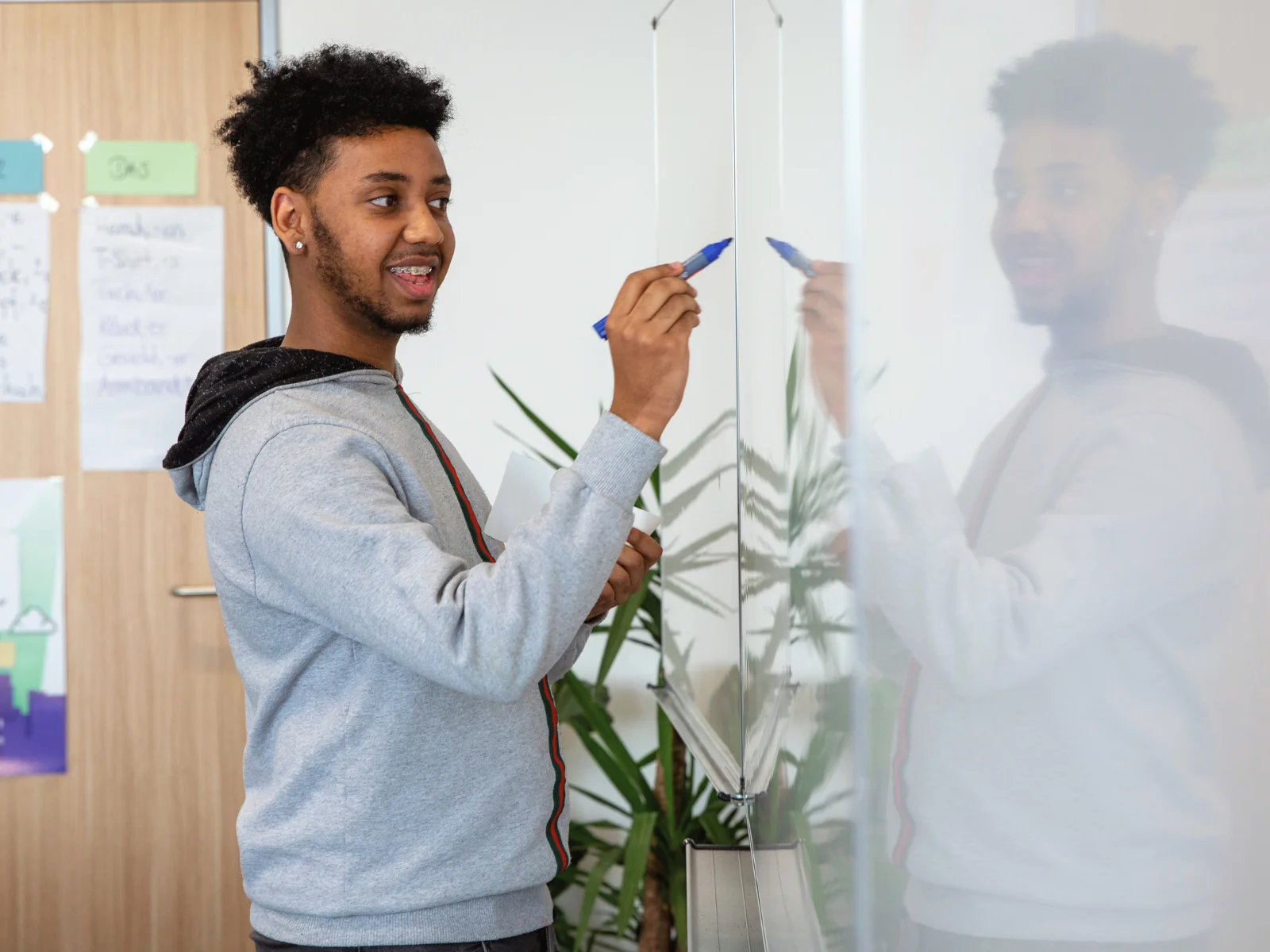 Schüler schreibt lächelnd an die Tafel im Alphabetisierungsunterricht