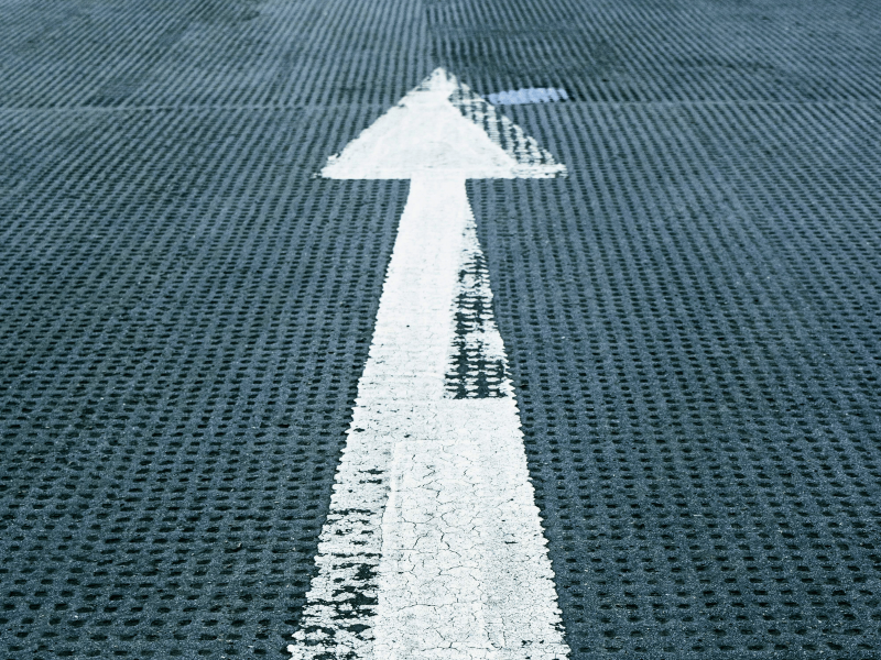 Wegweiser für das Projekt SchlaU:Ankommen; ein weißer Pfeil zeigt auf einer Straße nach oben