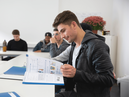deutsch-als-zweitsprache Schüler sitzt im Klassenraum und blättert durch DaZ-Lernmaterial