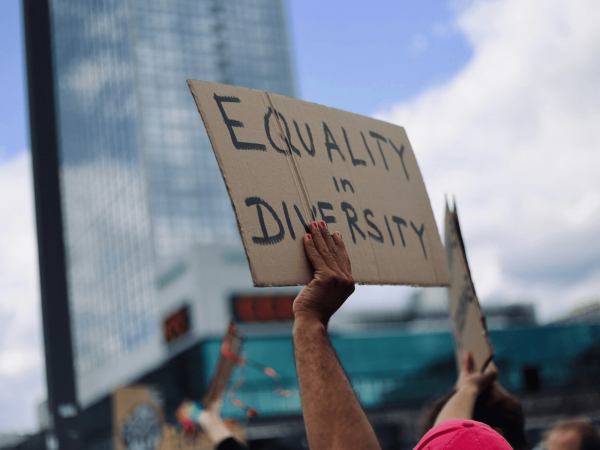 ein Schild wird hochgehoben auf dem "Equality in Diversity" steht