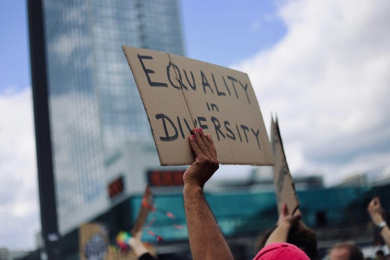 eine Person hält ein Schild hoch auf dem steht: Equality and Diversity